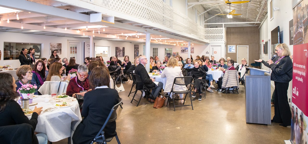 Women gathered at tables listening to a speaker at a Women's Philanthropy Brunch Club gathering