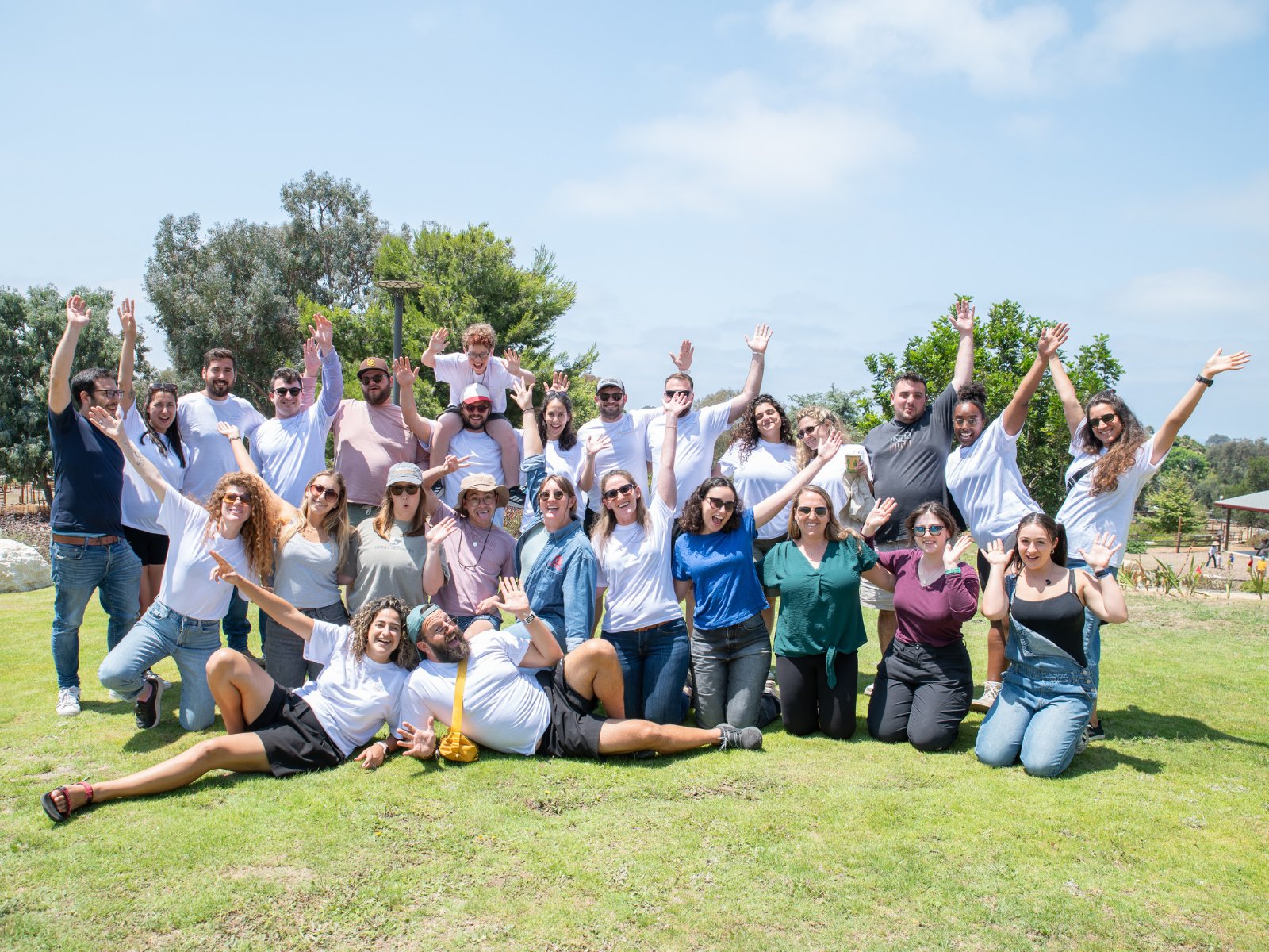 A group of Jewish young adults waving together on a sunny lawn in San Diego