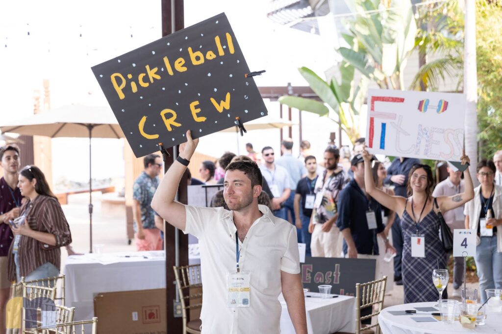 A member holds up a Pickleball Crew sign while another holds a Fitness sign at the Mosaic launch on Shelter Island