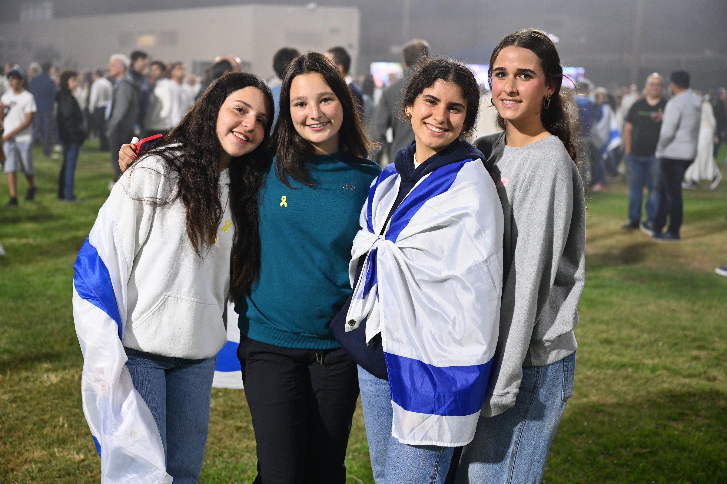 Four San Diego teens wrapped in Israeli flags at a community gathering